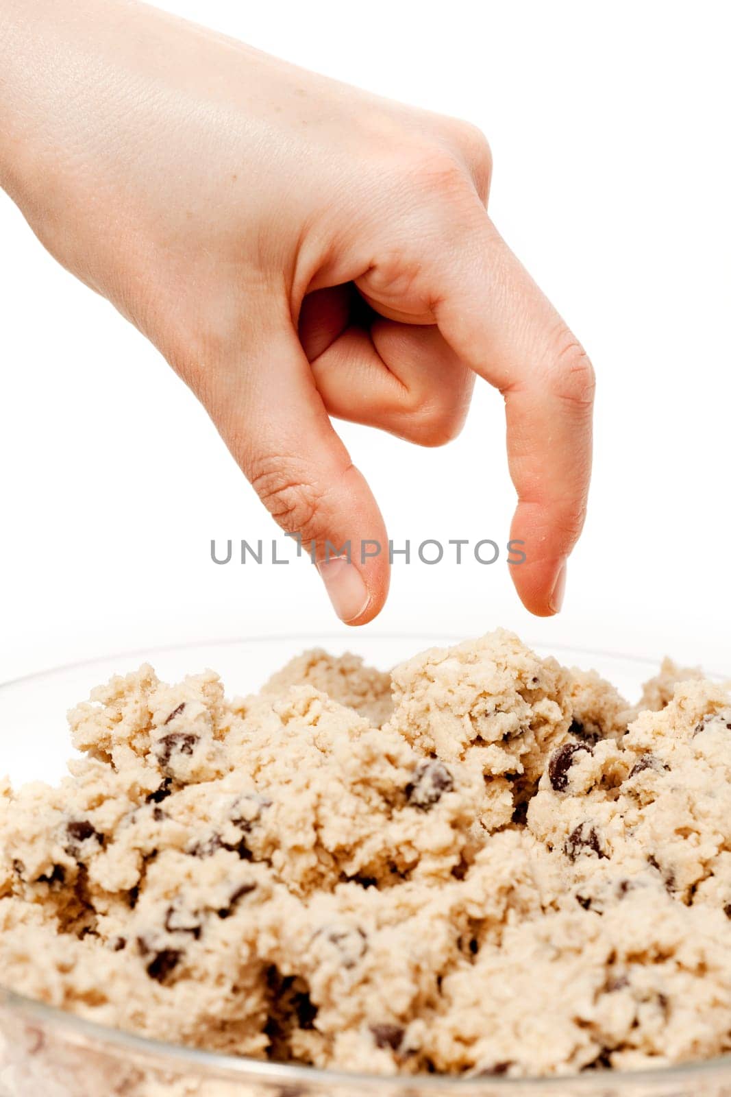 A hand reaching for a bowl of raw cookie dough