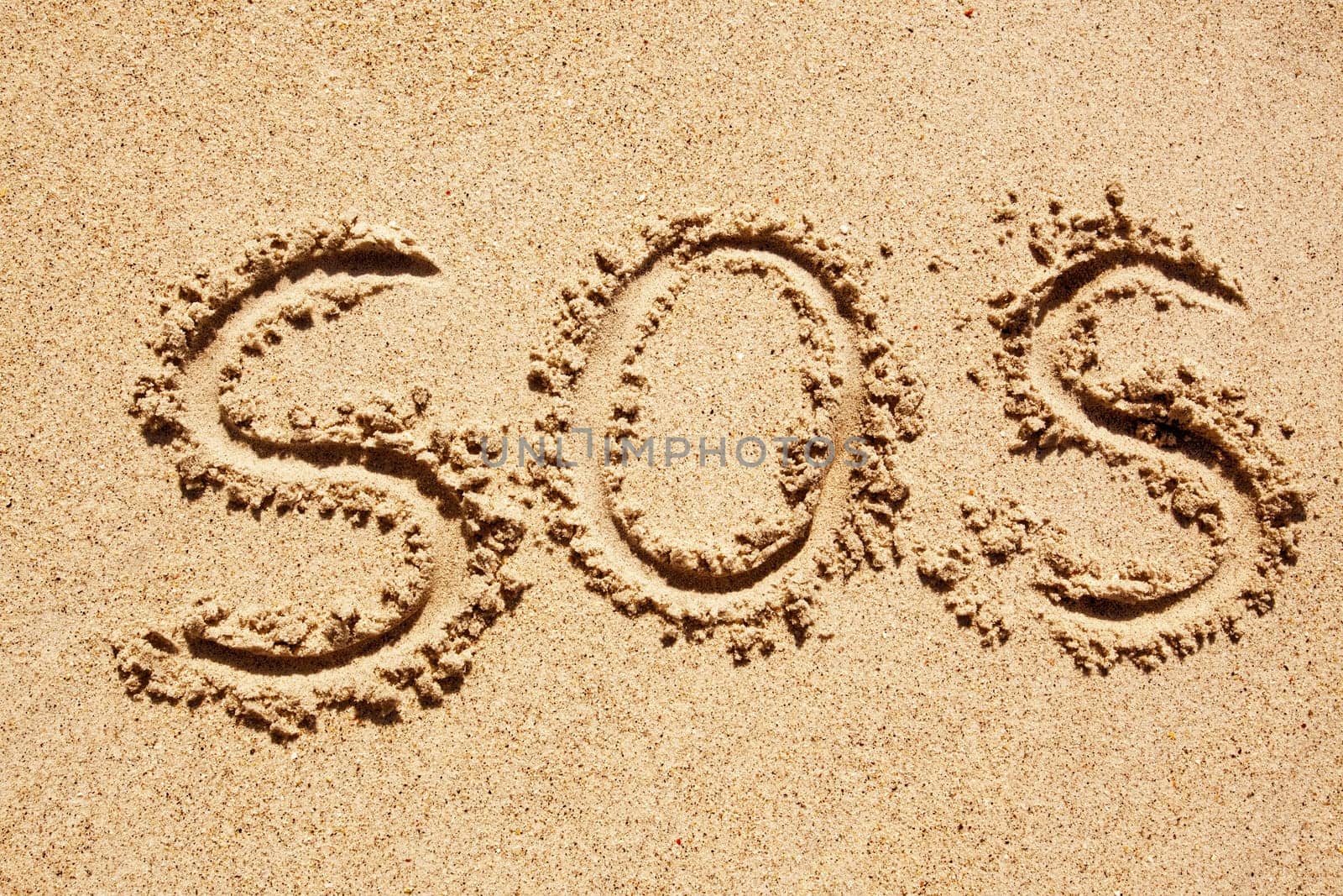 S.O.S written in the sand with a finger or stick