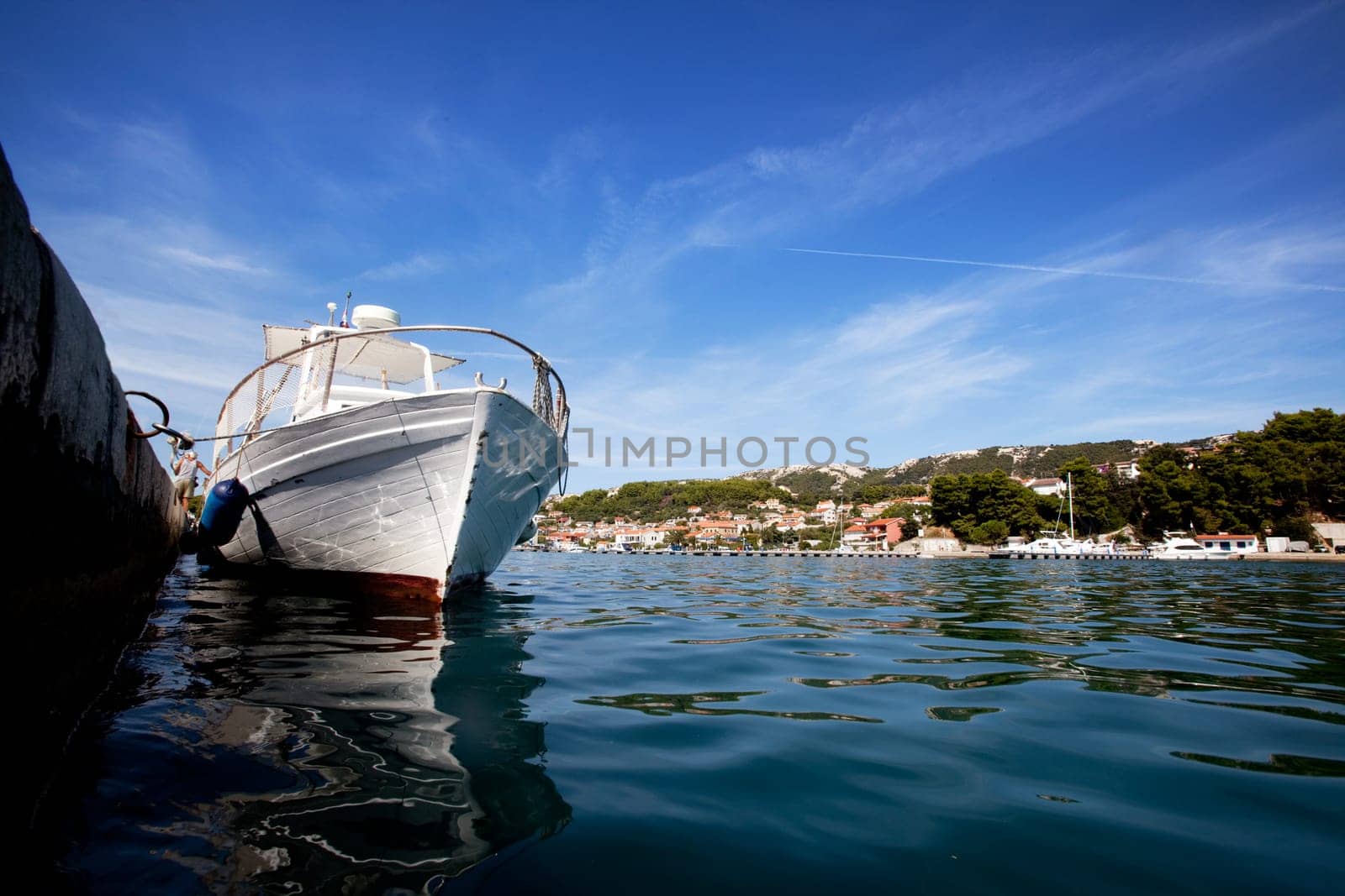 A wooden bat tied to a stone dock in old town Rab, Croatia