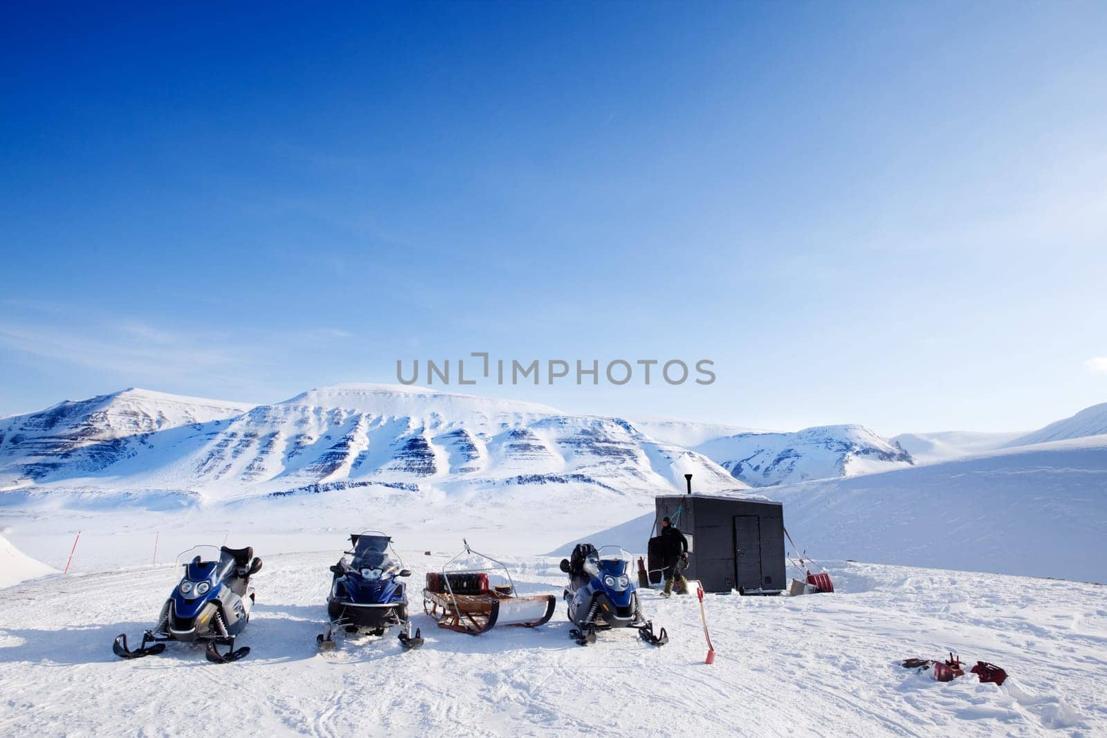 People preparing snowmobiles for an expedition through through winter conditions