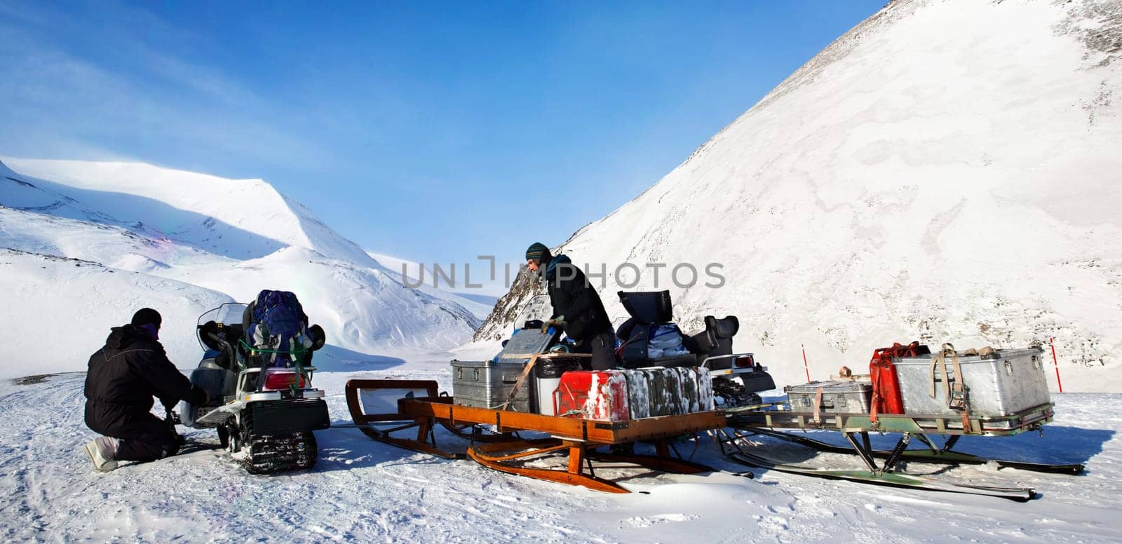 People preparing snowmobiles for an expedition through through winter conditions