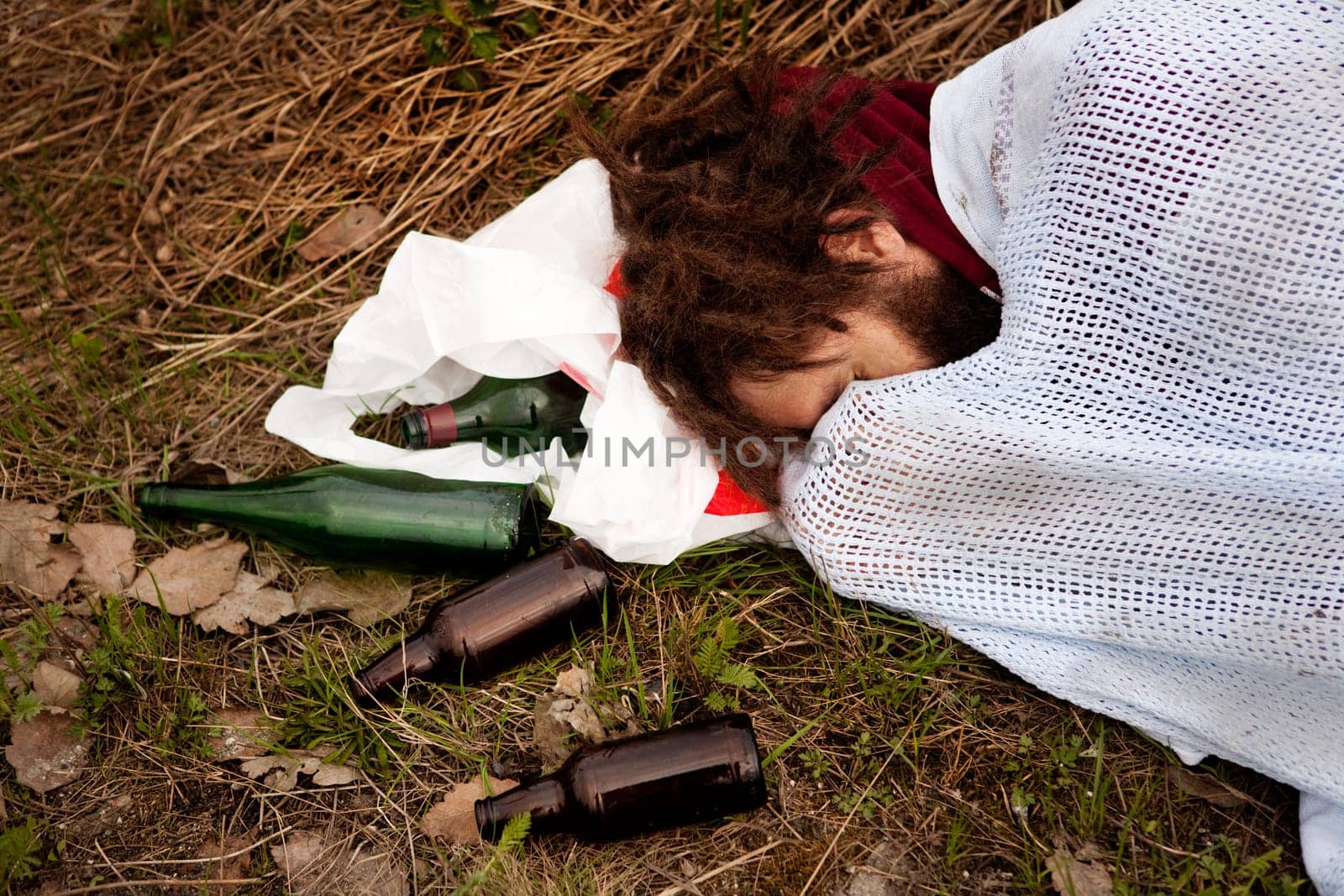 A person drunk sleeping in the ditch with liquor bottles