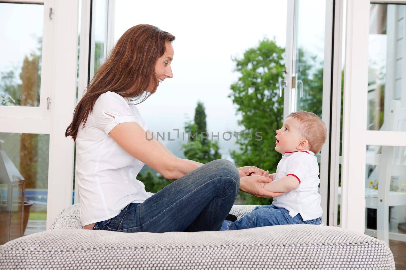 Young mother sitting on couch and looking at innocent child