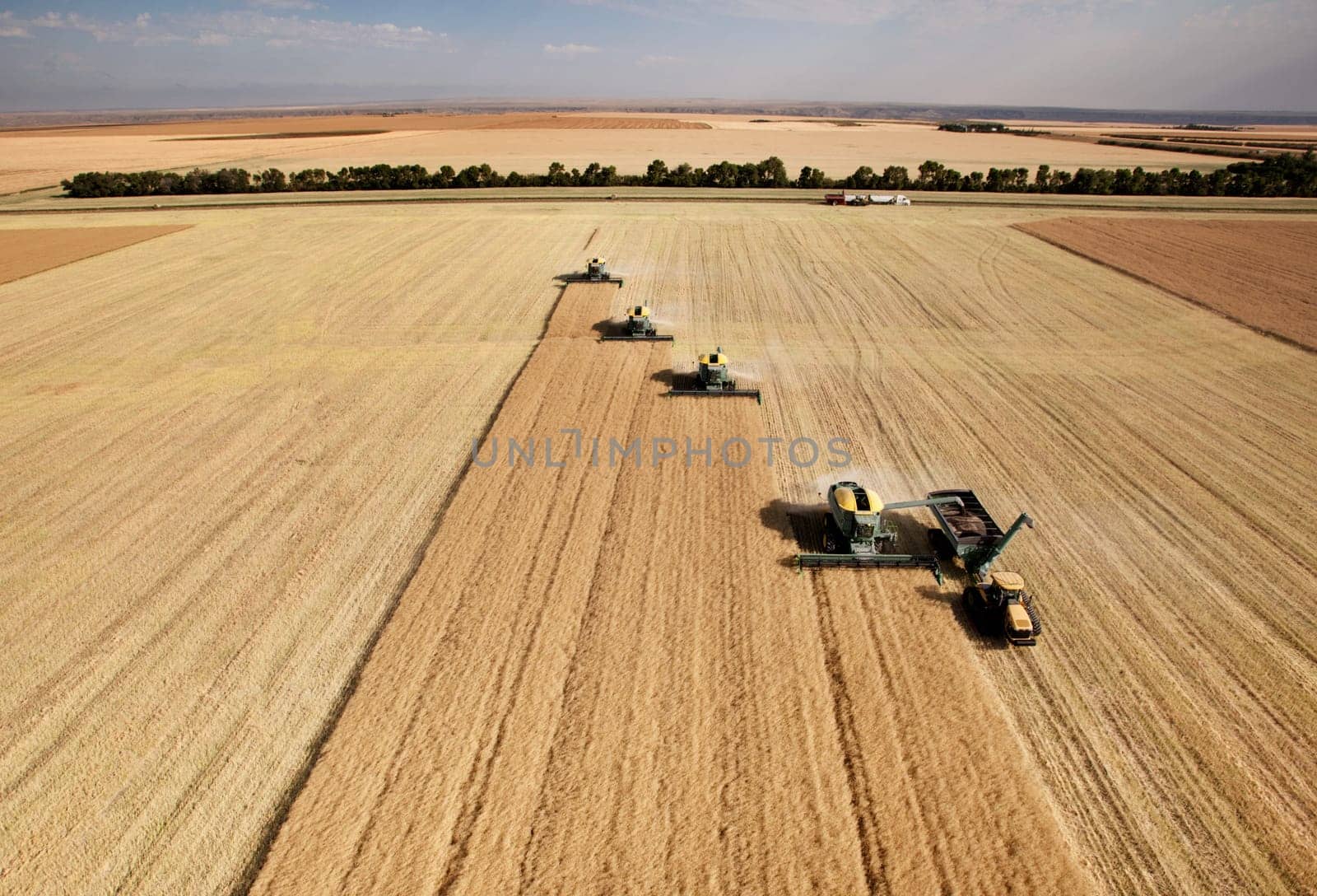 Four harvesters combing on a prairie landscape in formation