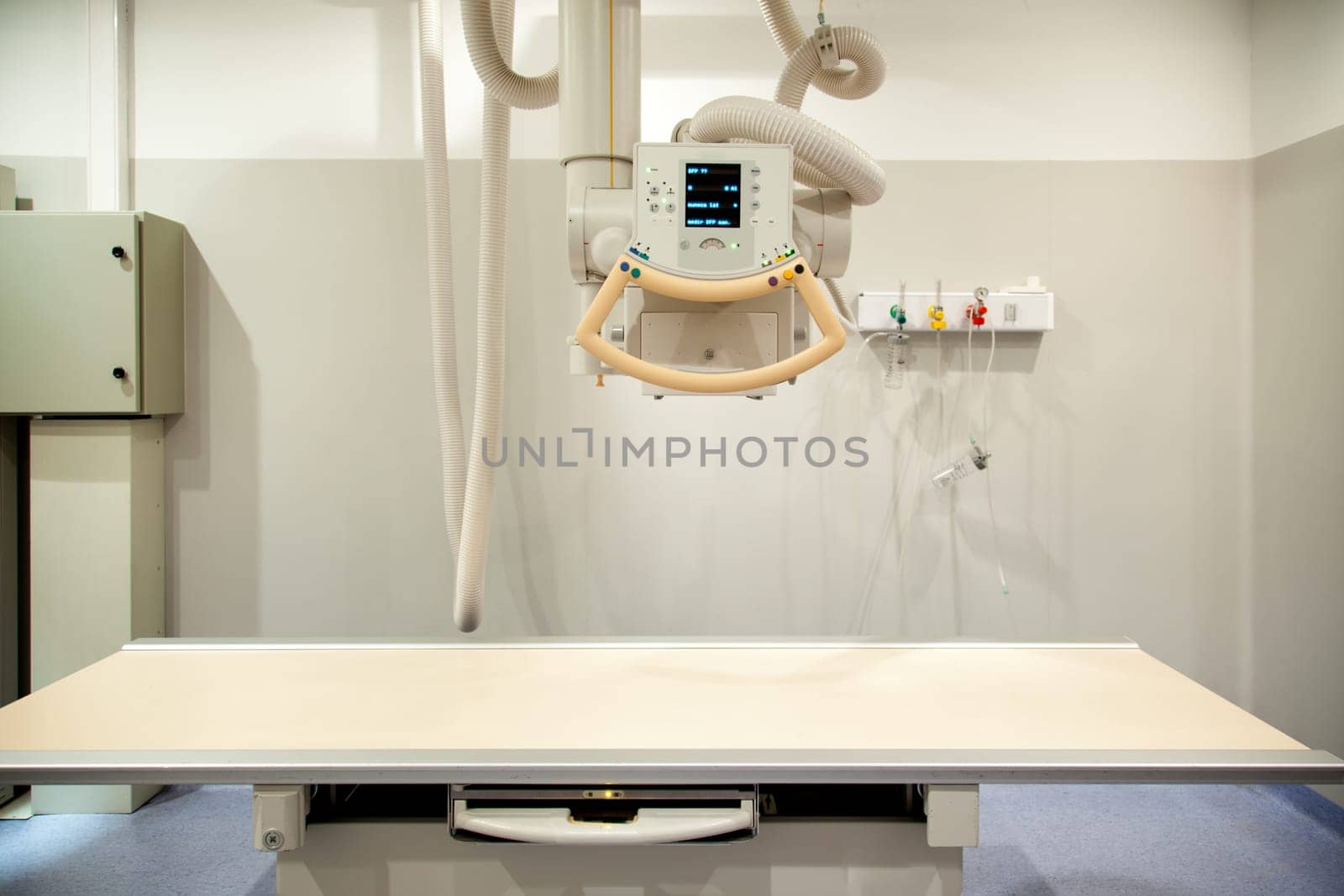 An empty x-ray room with an x-ray machine and table