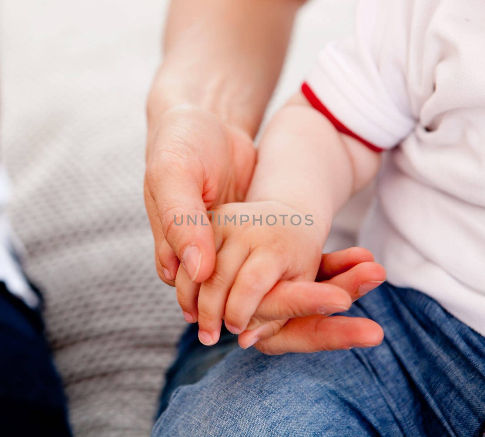Detail of a small toddler boy holding his mothers hand