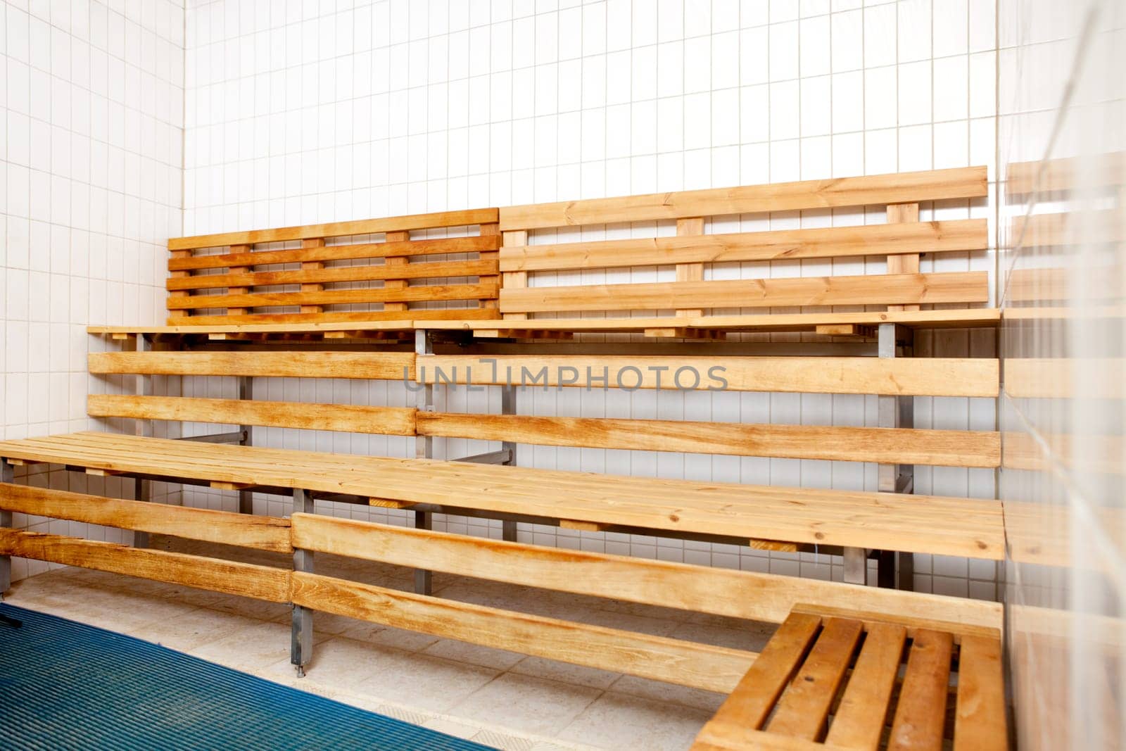 An empty sauna interior with tile walls and wood seats