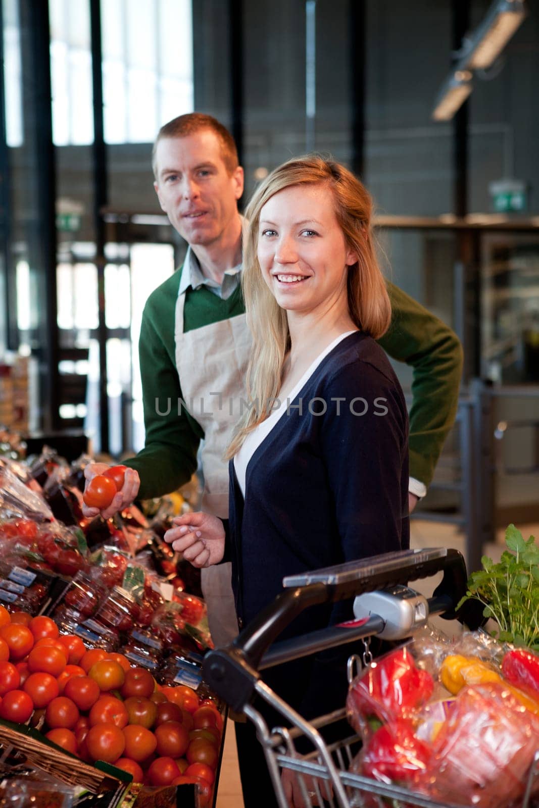 A woman buying fruit at a supermarket receiving help from a store clerk
