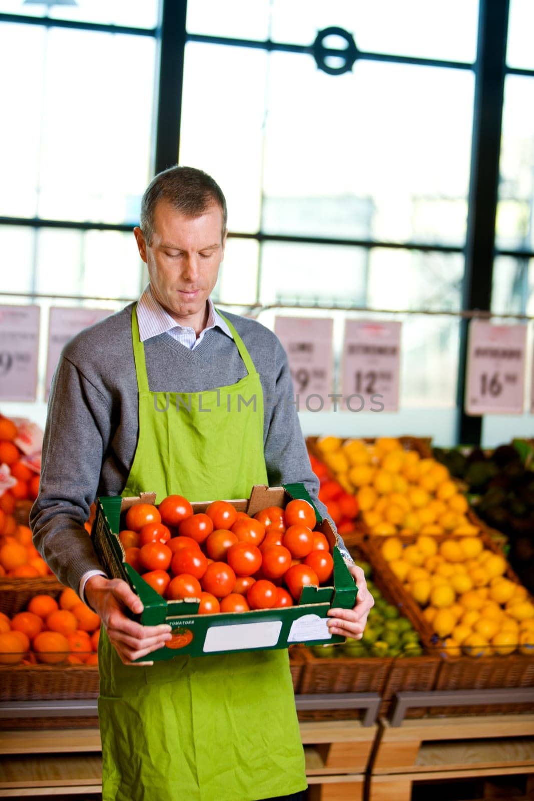 A male grocery owner with a box of ripe tomatoes