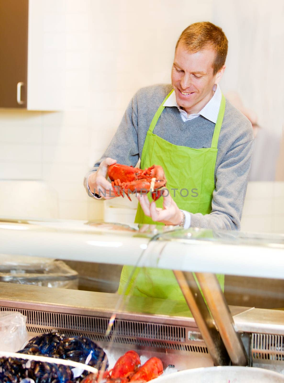 A fresh fish counter in a grocery store - clerk with a lobster