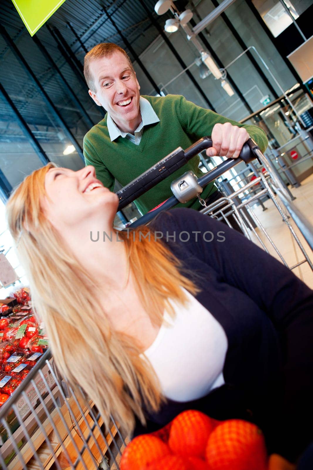 A woman in a shopping cart - a playful crazy couple in a supermarket