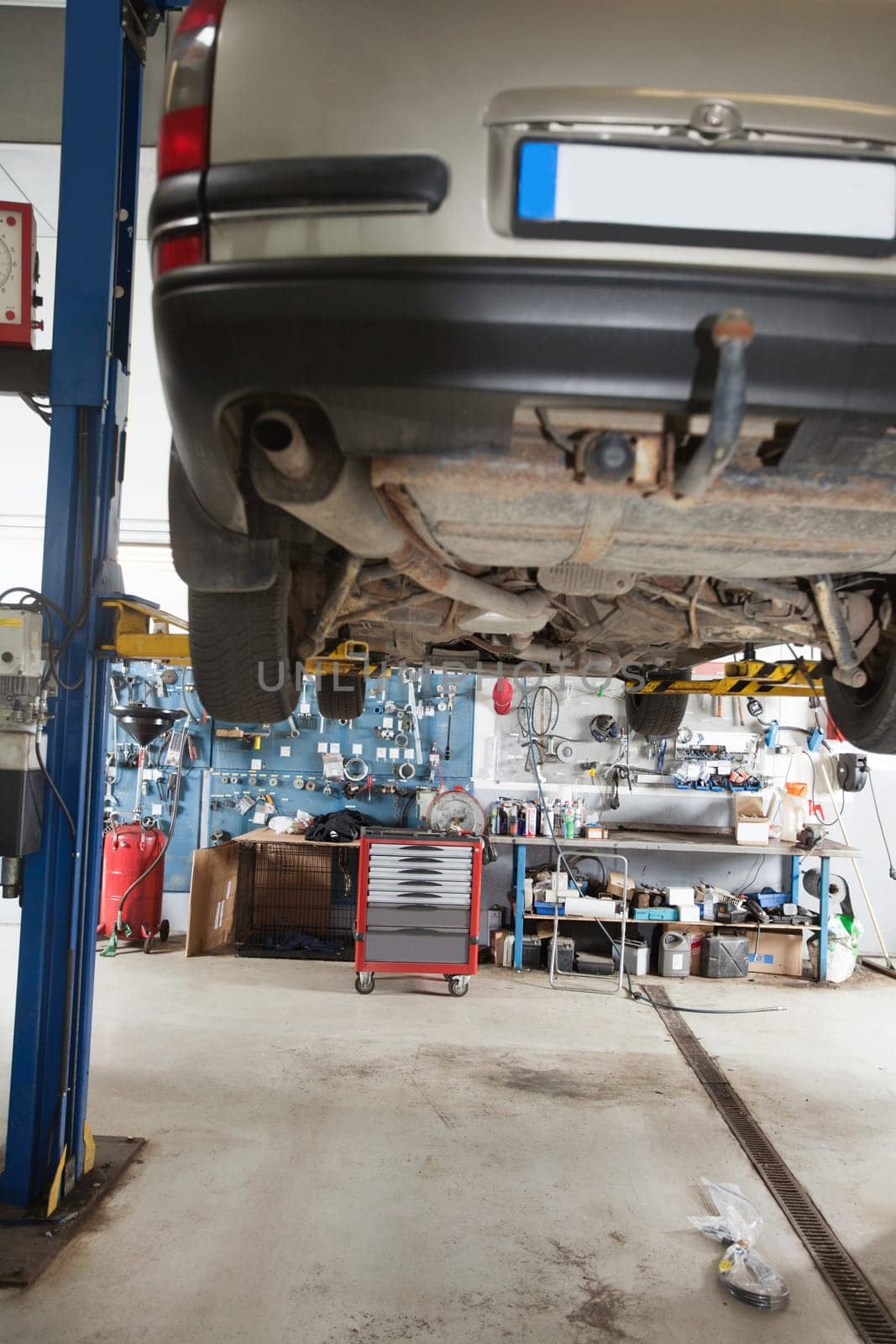 Car under repair on service lift in garage