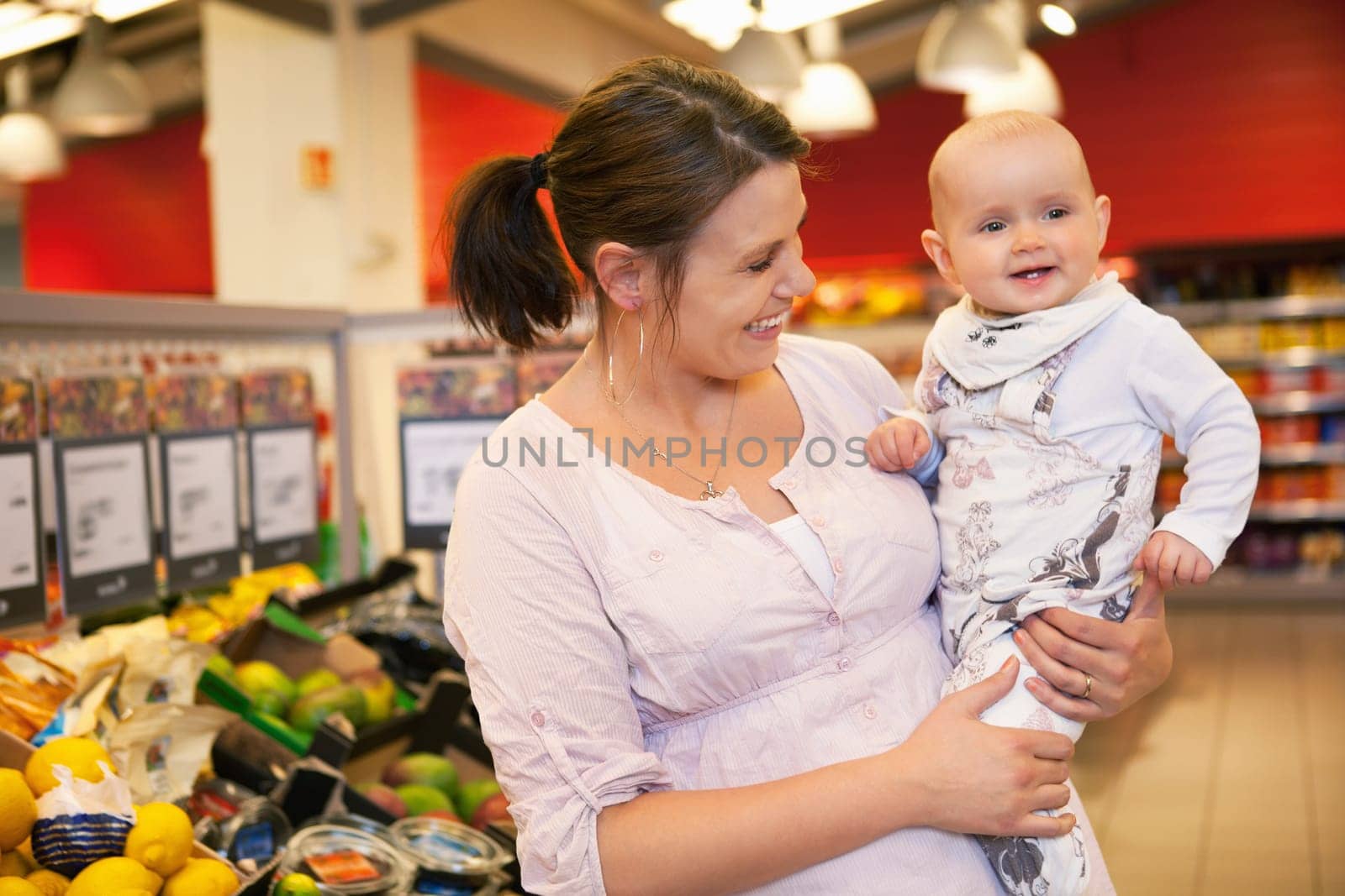 Happy mother carrying child in supermarket