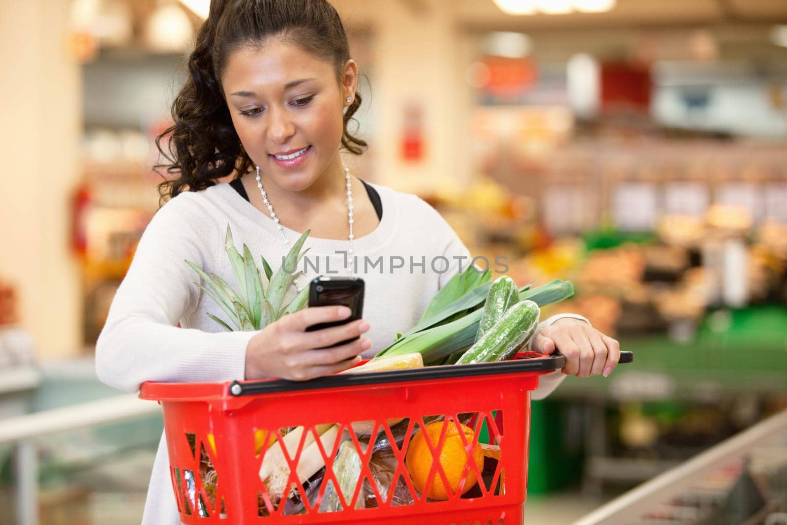 Smiling young woman using mobile phone while shopping in shopping store