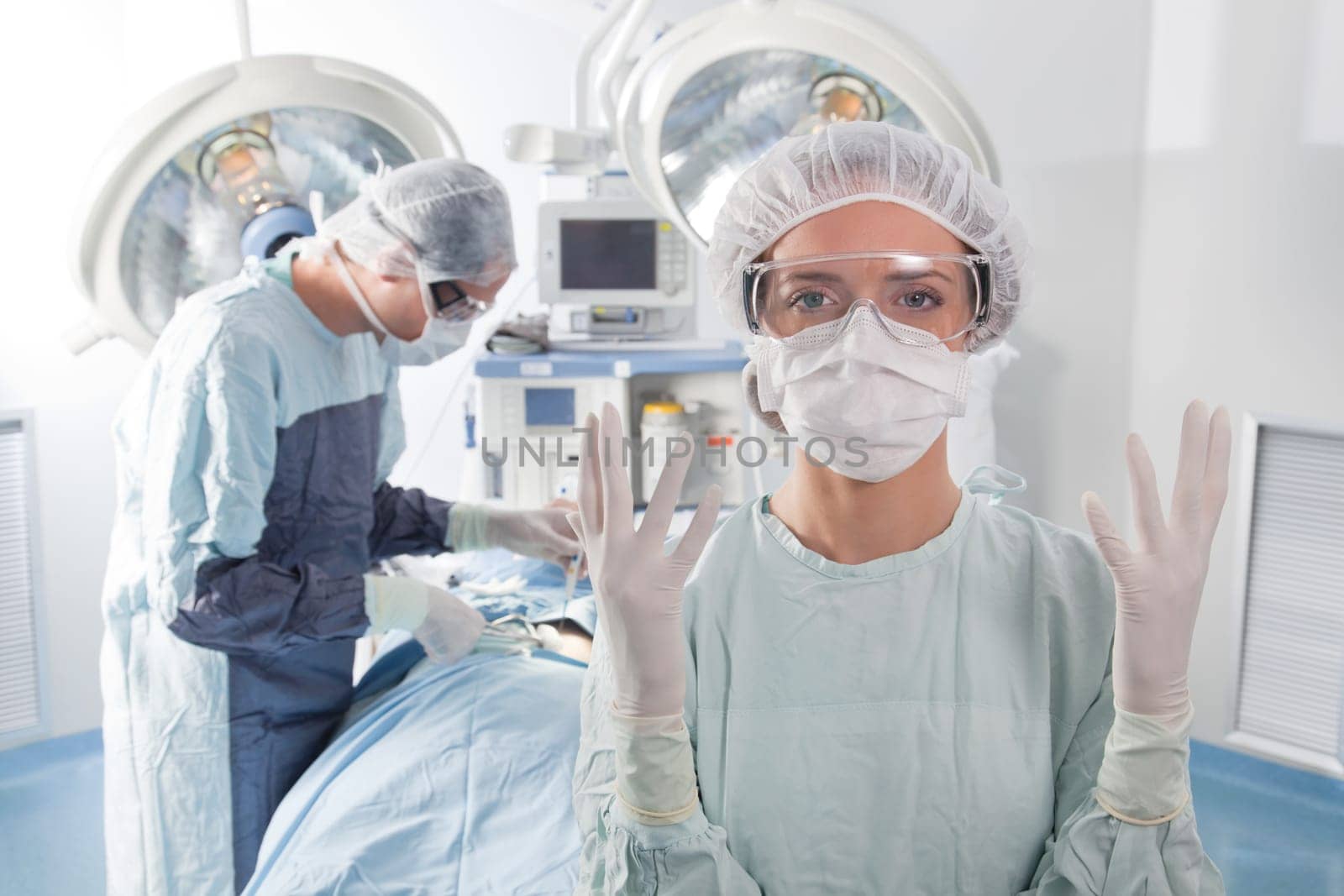 Close-up of female surgeon asking for gloves in middle of operation