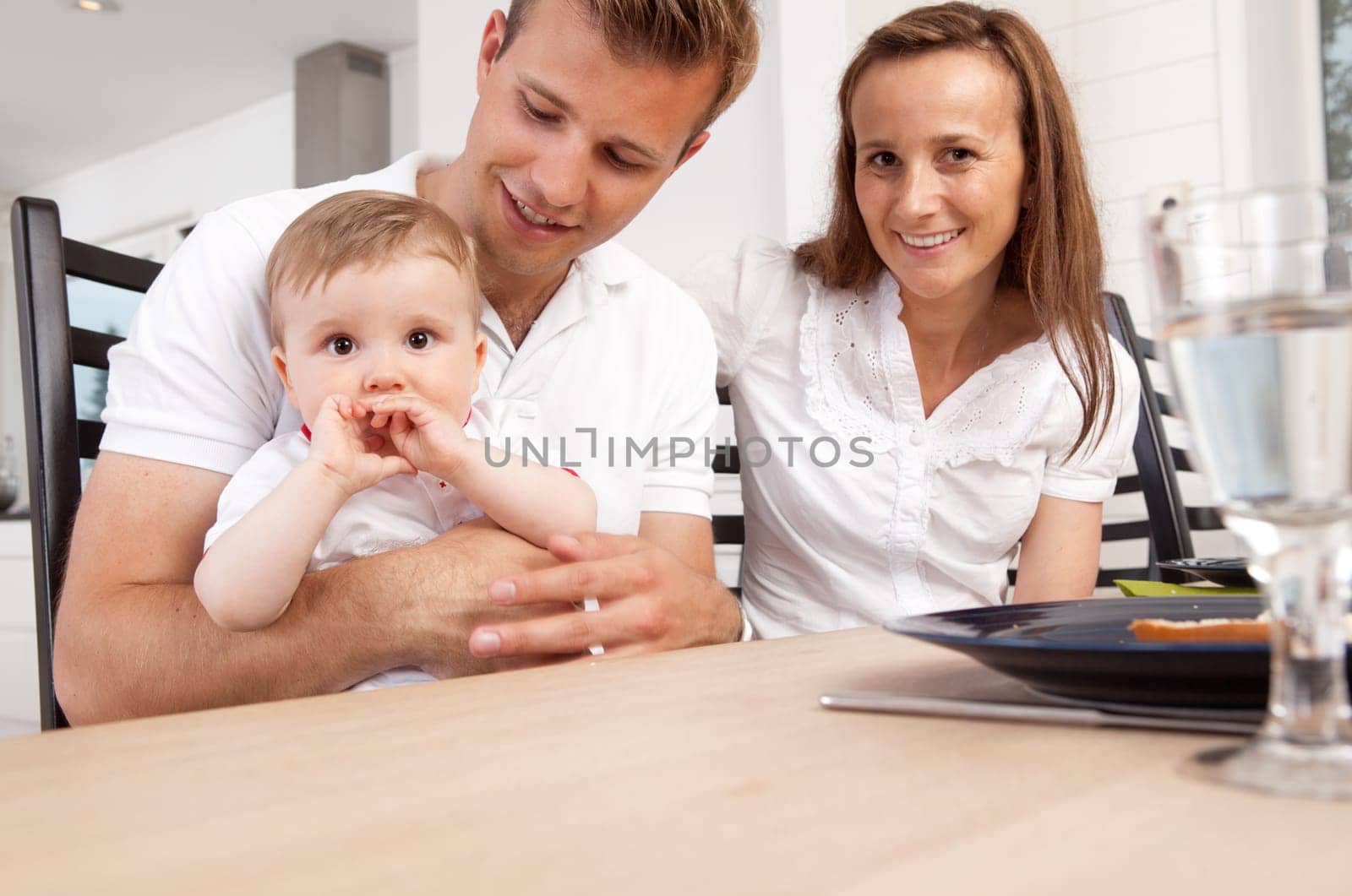 Portrait of happy small family at home at dinner table