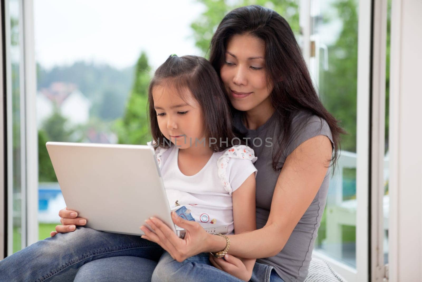 Young mother and daughter at home looking at laptop