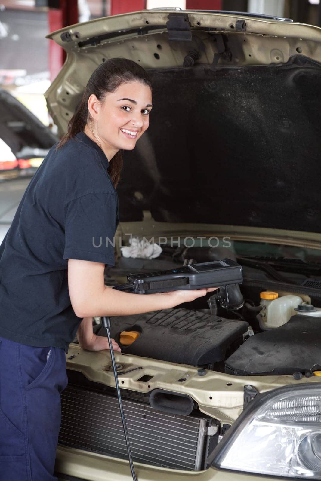 A happy female mechanic looking at the camera using a diagnostic scan tool