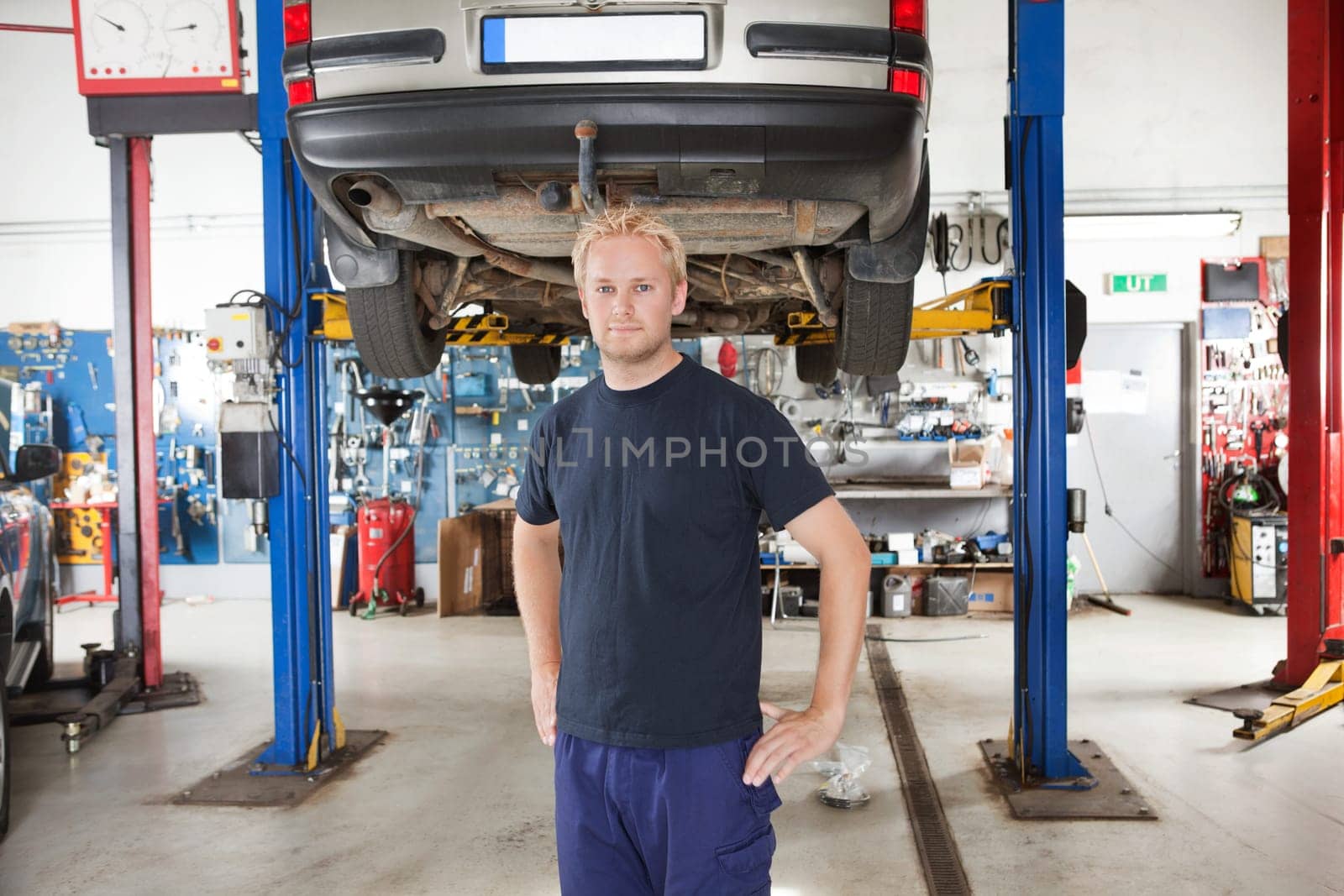 Portrait of smiling young mechanic standing inside his auto repair shop