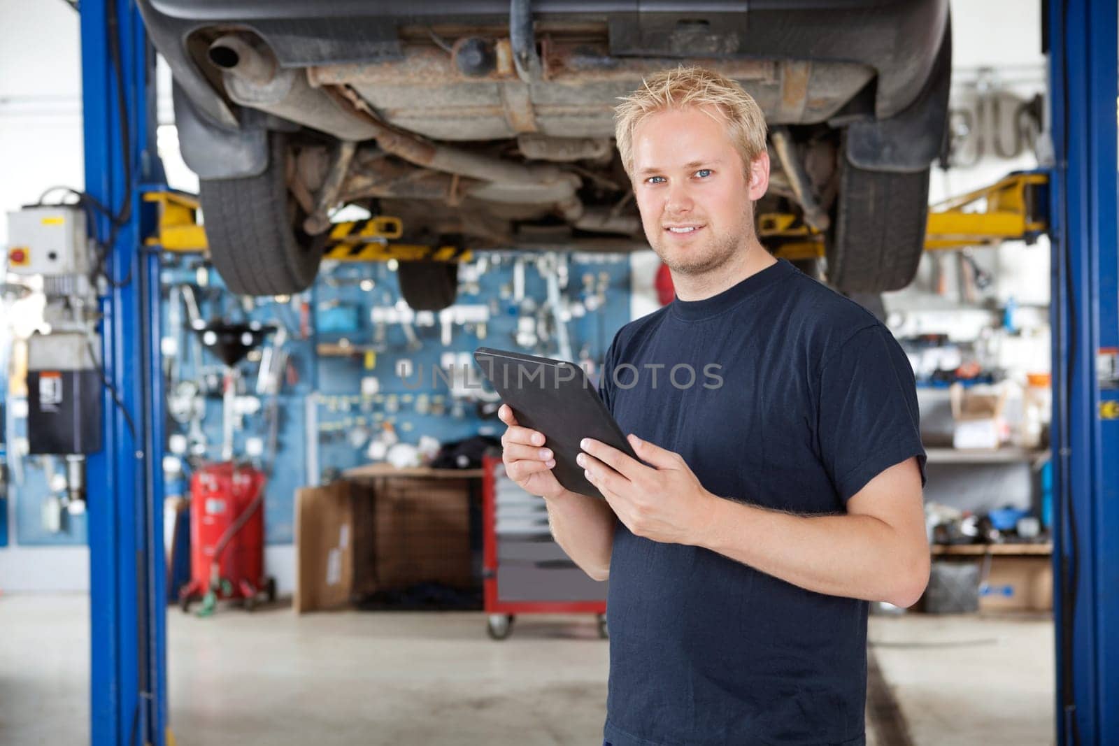 Portrait of young mechanic holding digital tablet in his auto repair shop