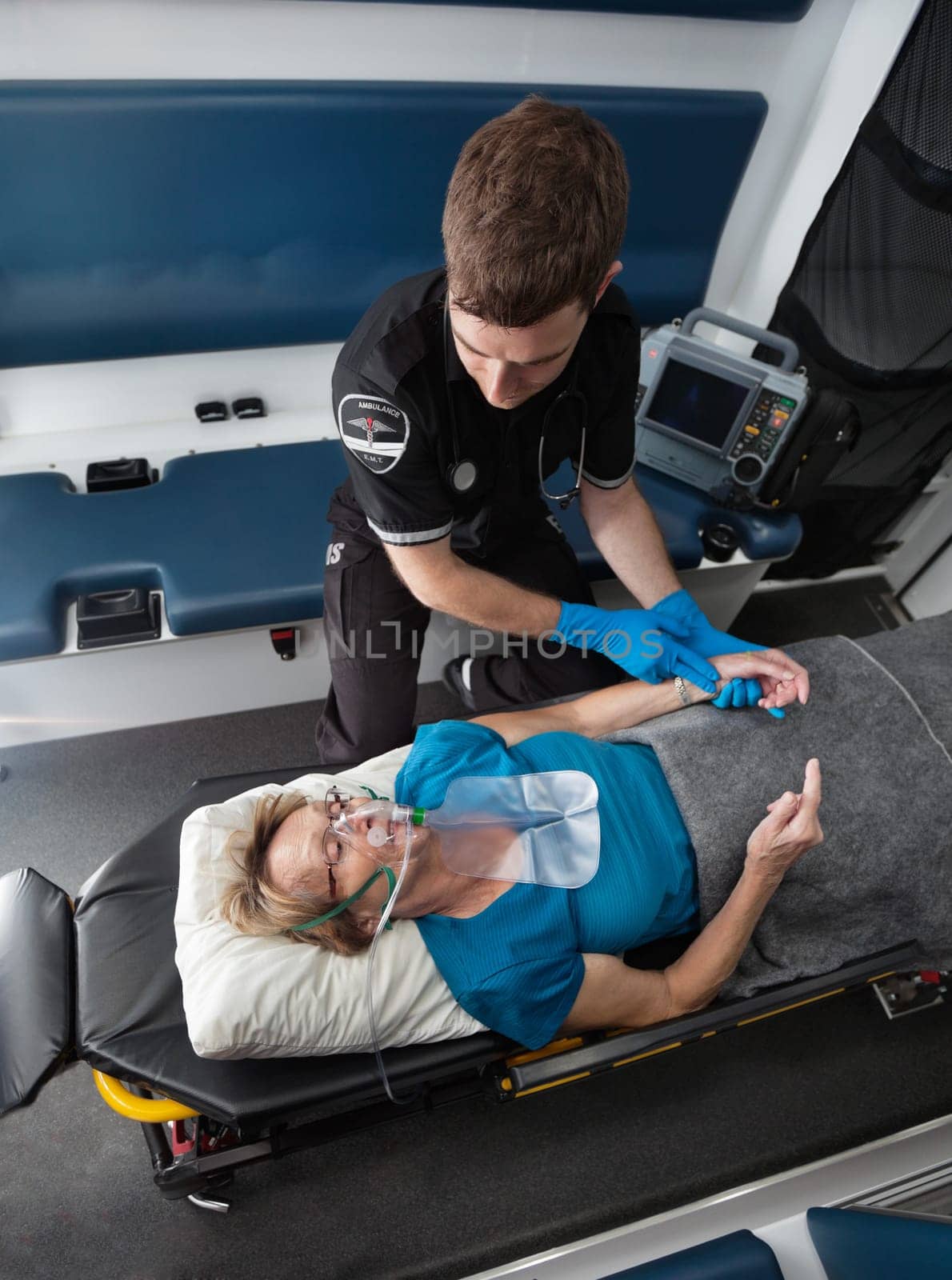 Male ambulance worker taking pulse of elderly senior woman
