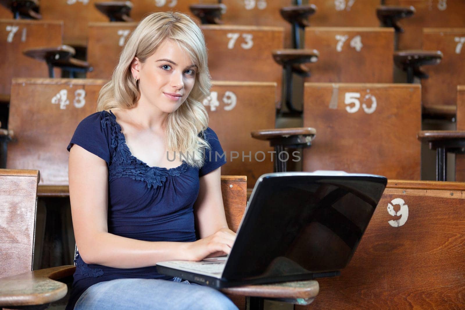 Portrait of young girl using laptop in lecture theatre