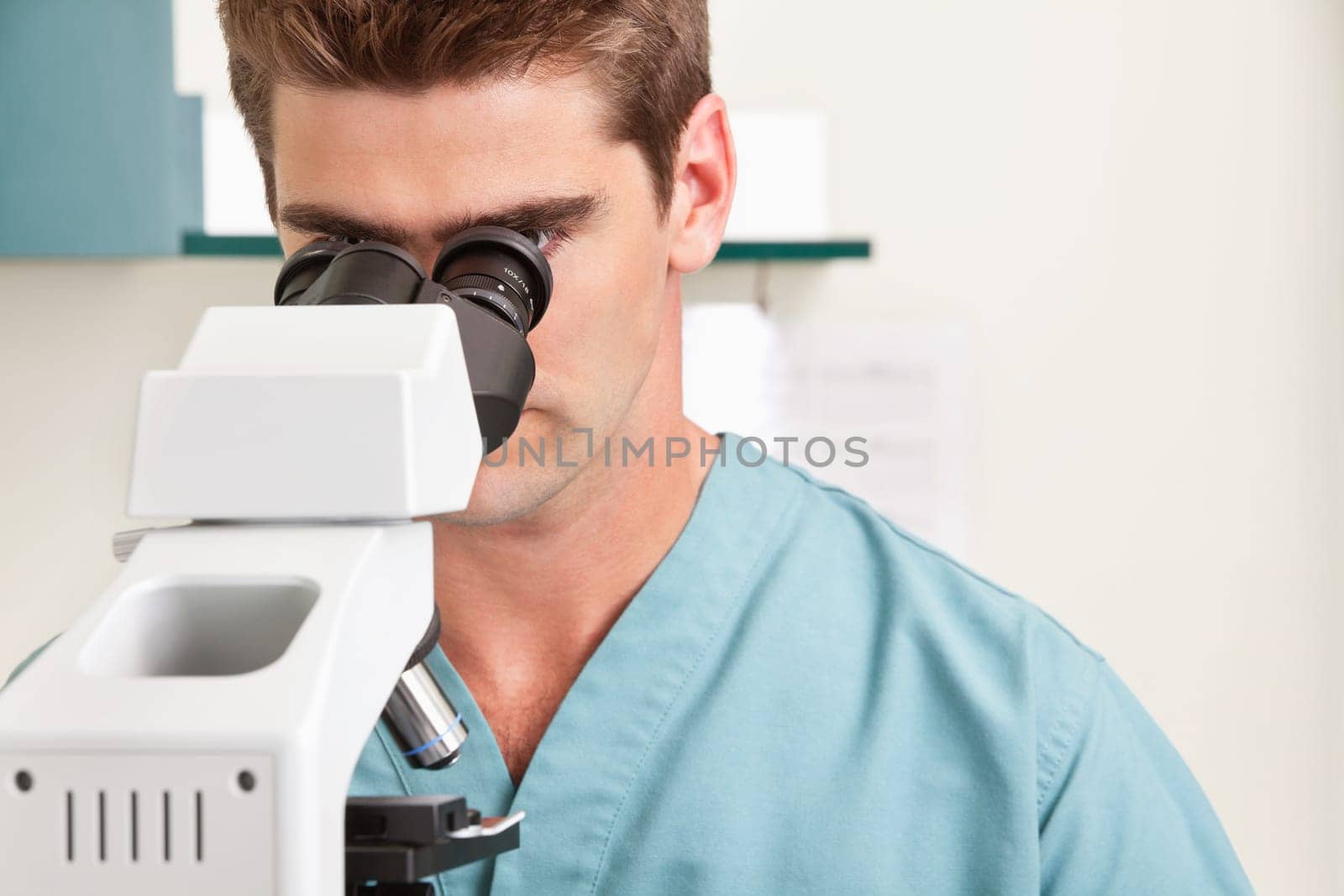 Closeup of young male doctor viewing through microscope