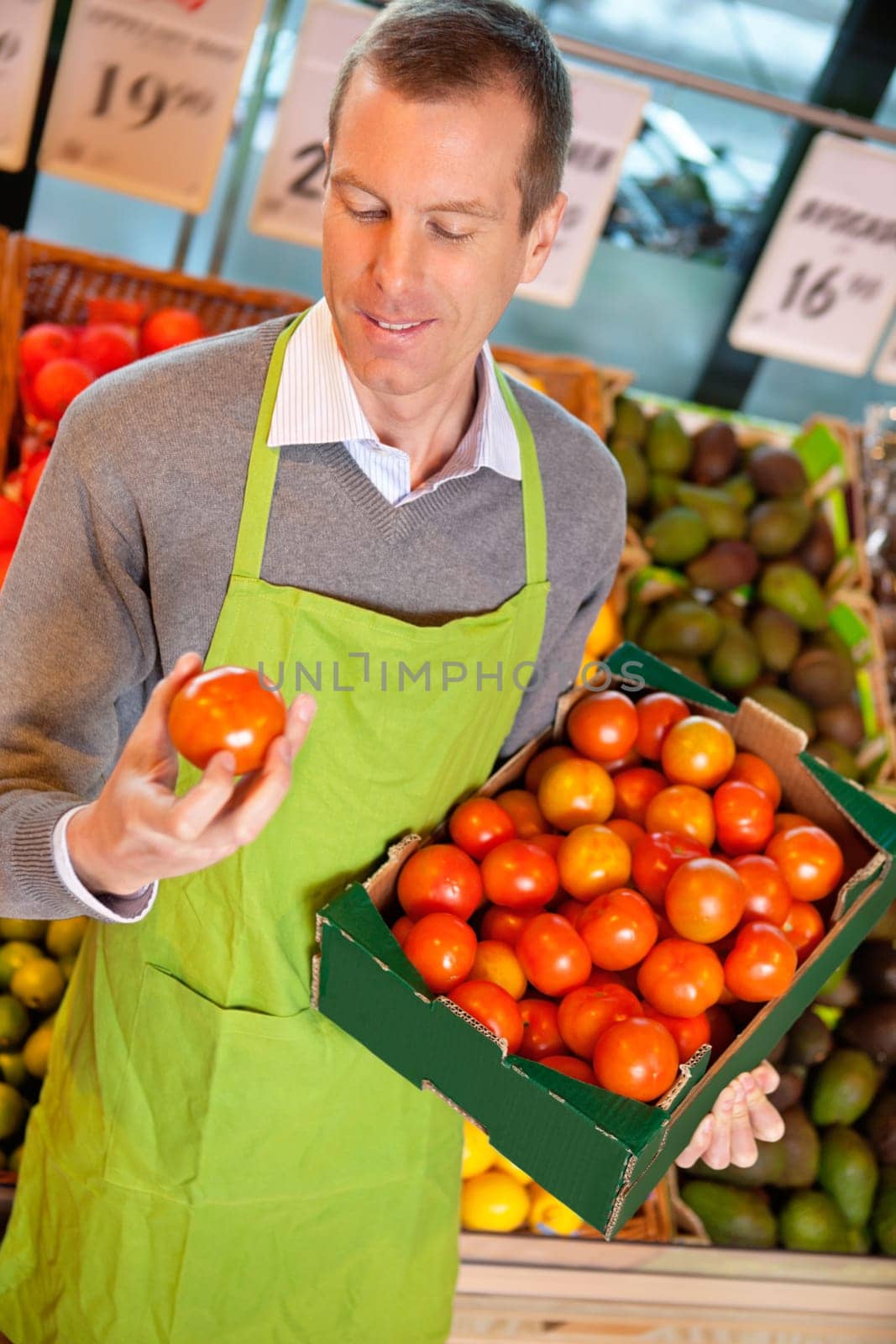 Closeup of a market assistant holding box of tomatoes in the supermarket