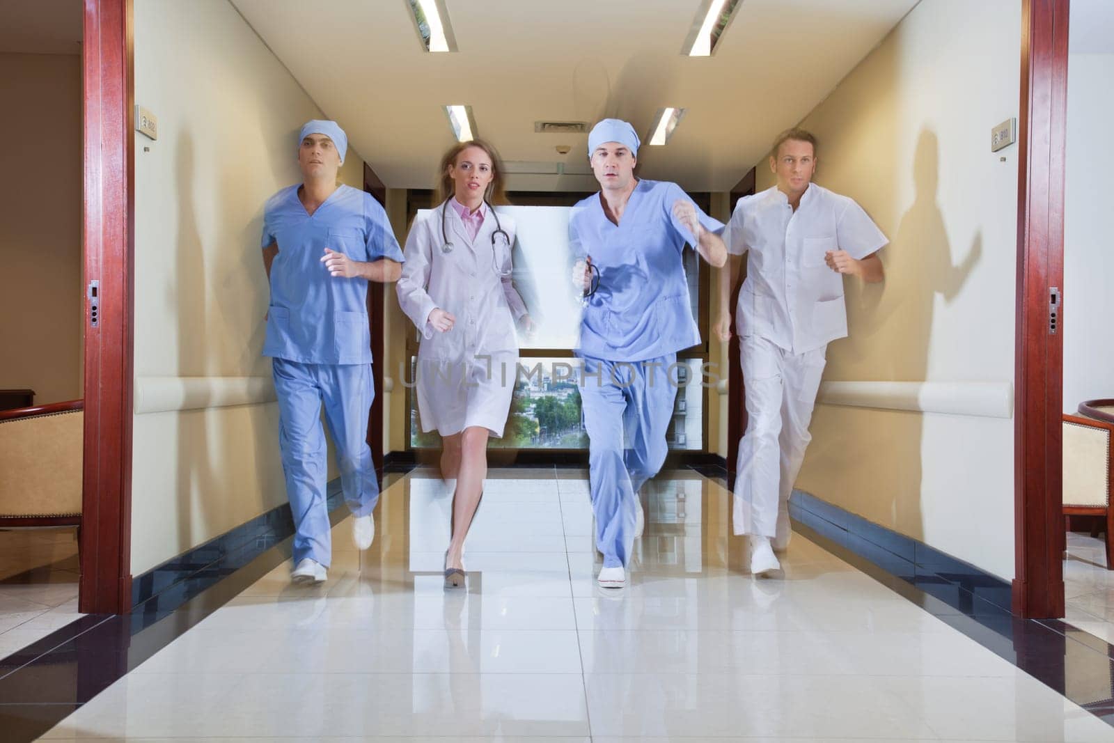 Team of surgeon and nurse running in hallway of hospital