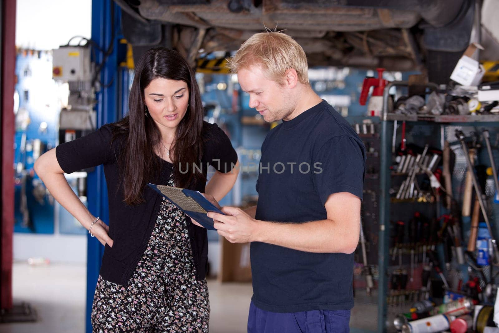 A happy customer looking at the service report in a mechanic shop