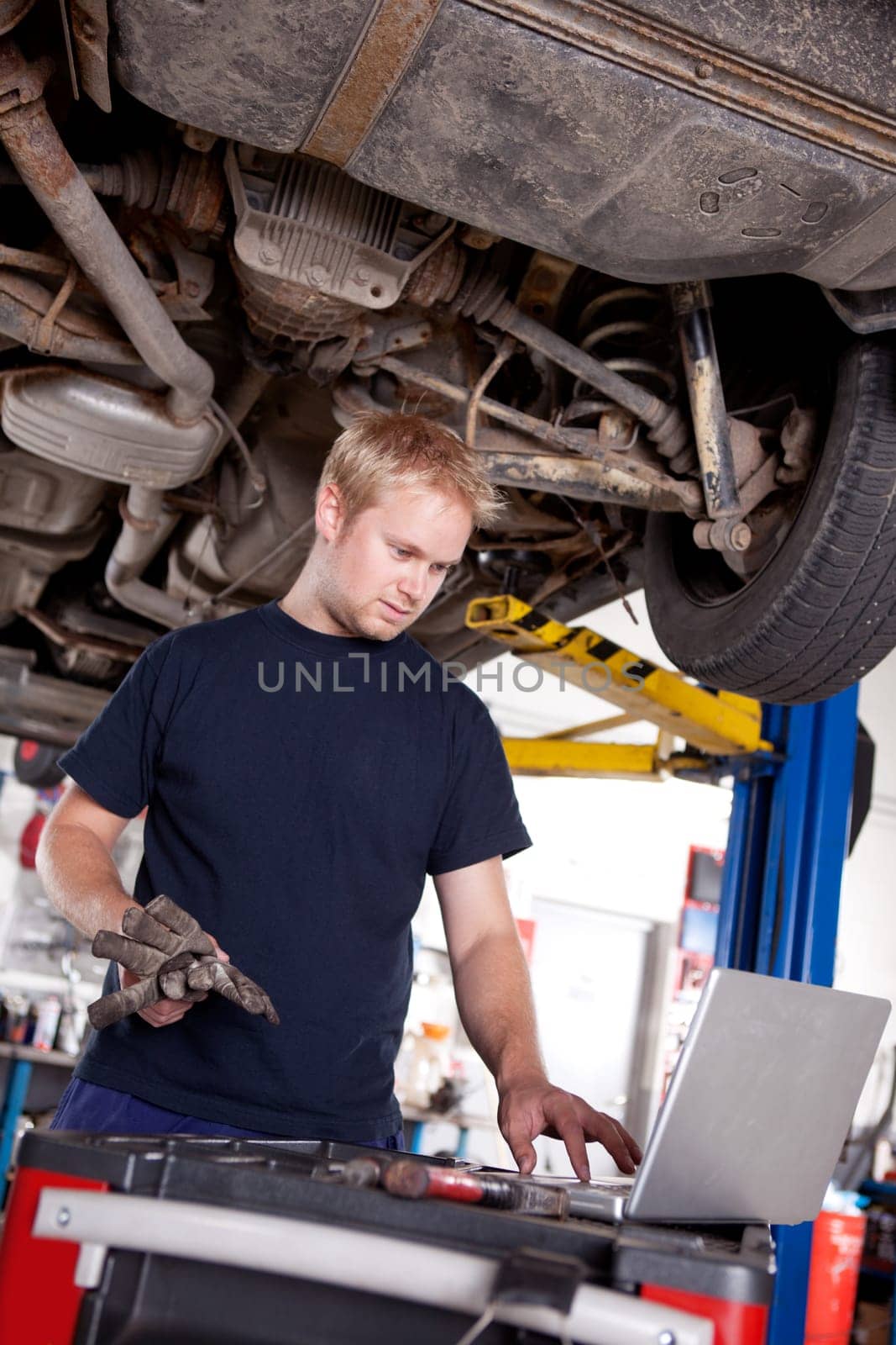 A mechanic in a garage looking at a laptop