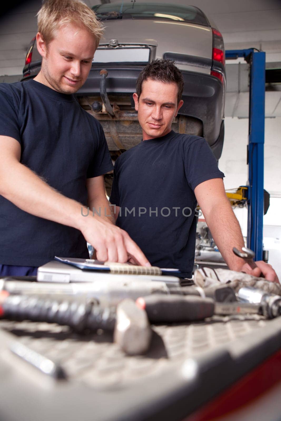 Two mechanics looking at work order and discussing repairs