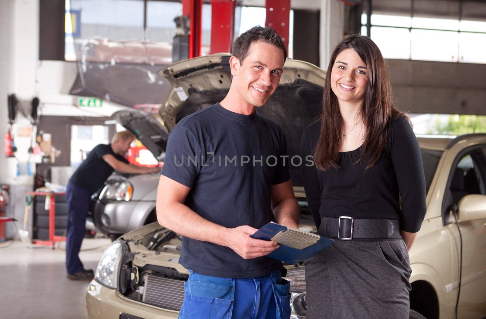 Portrait of a man mechanic with a woman customer going over the auto repair service report