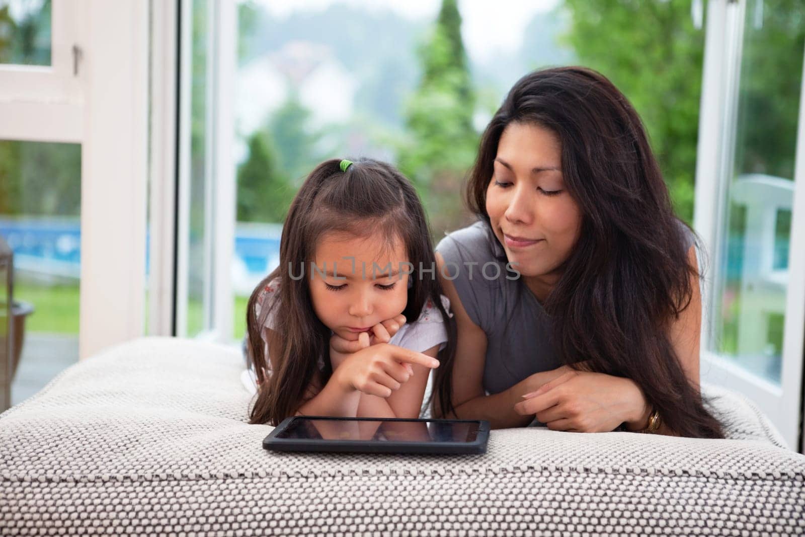 Mother and daughter playing with digital tblet at home