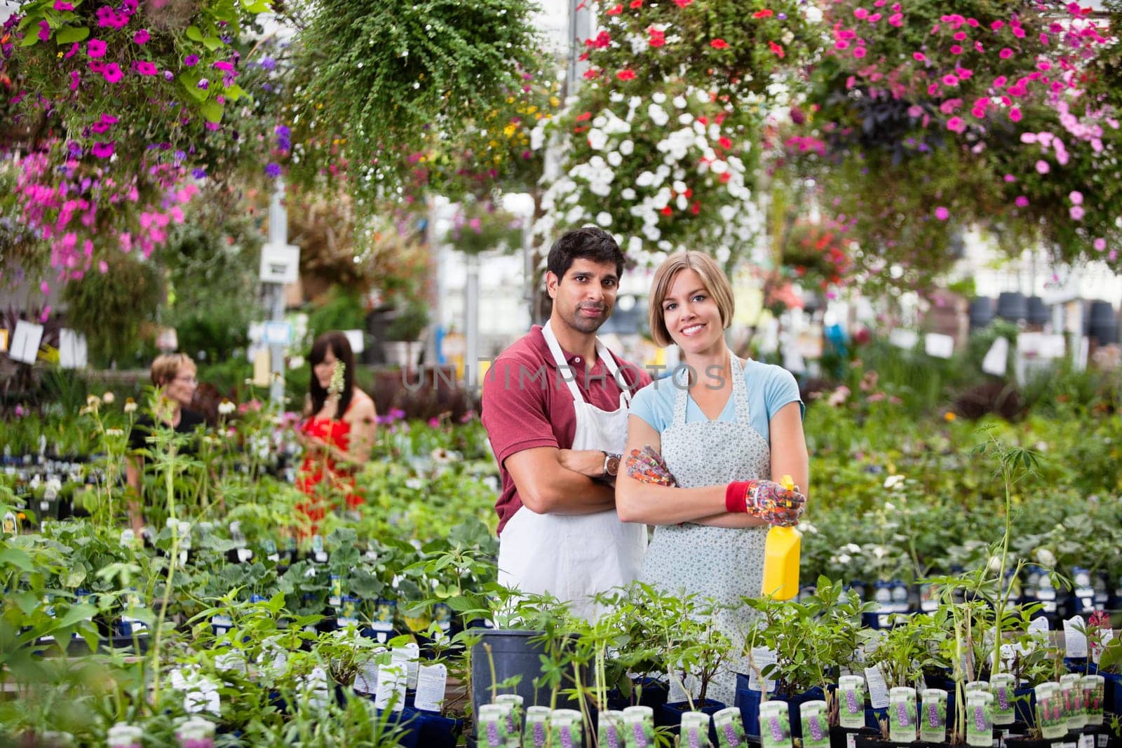 Portrait of florists at greenhouse with people in background