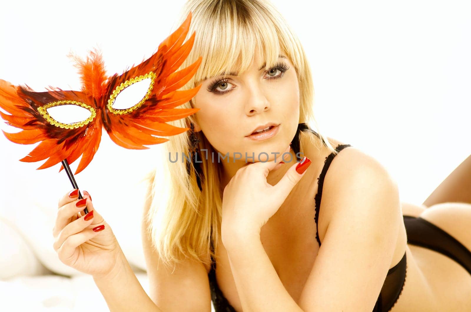 Portrait of attractive beautiful young woman on bed with red mask