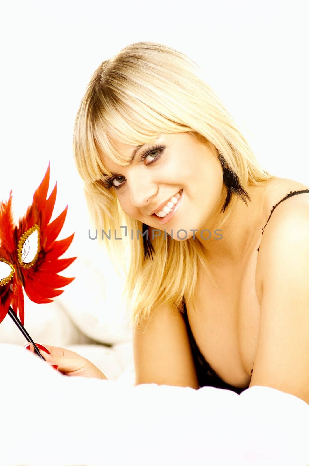 Portrait of attractive beautiful young woman on bed with red mask