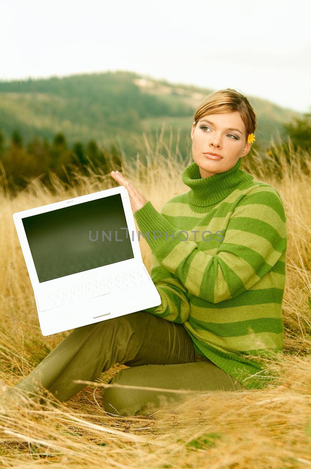 Young business woman holding laptop computer on golden meadow at mountains outdoors