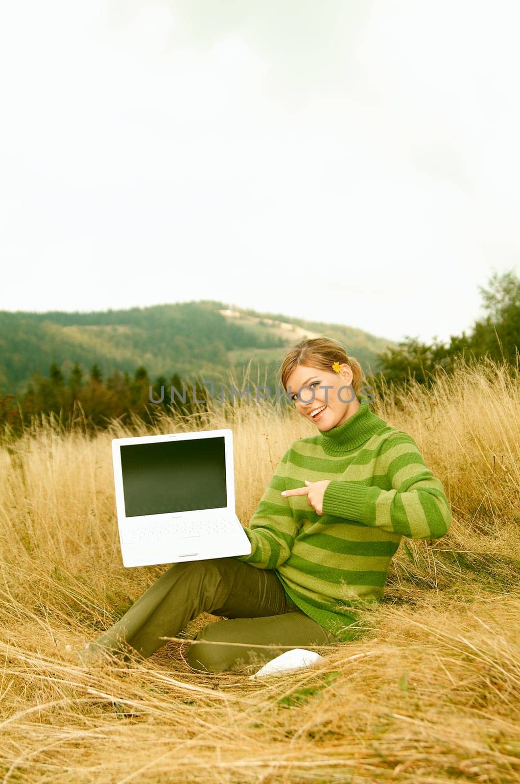 Young business woman holding laptop computer on golden meadow at mountains outdoors