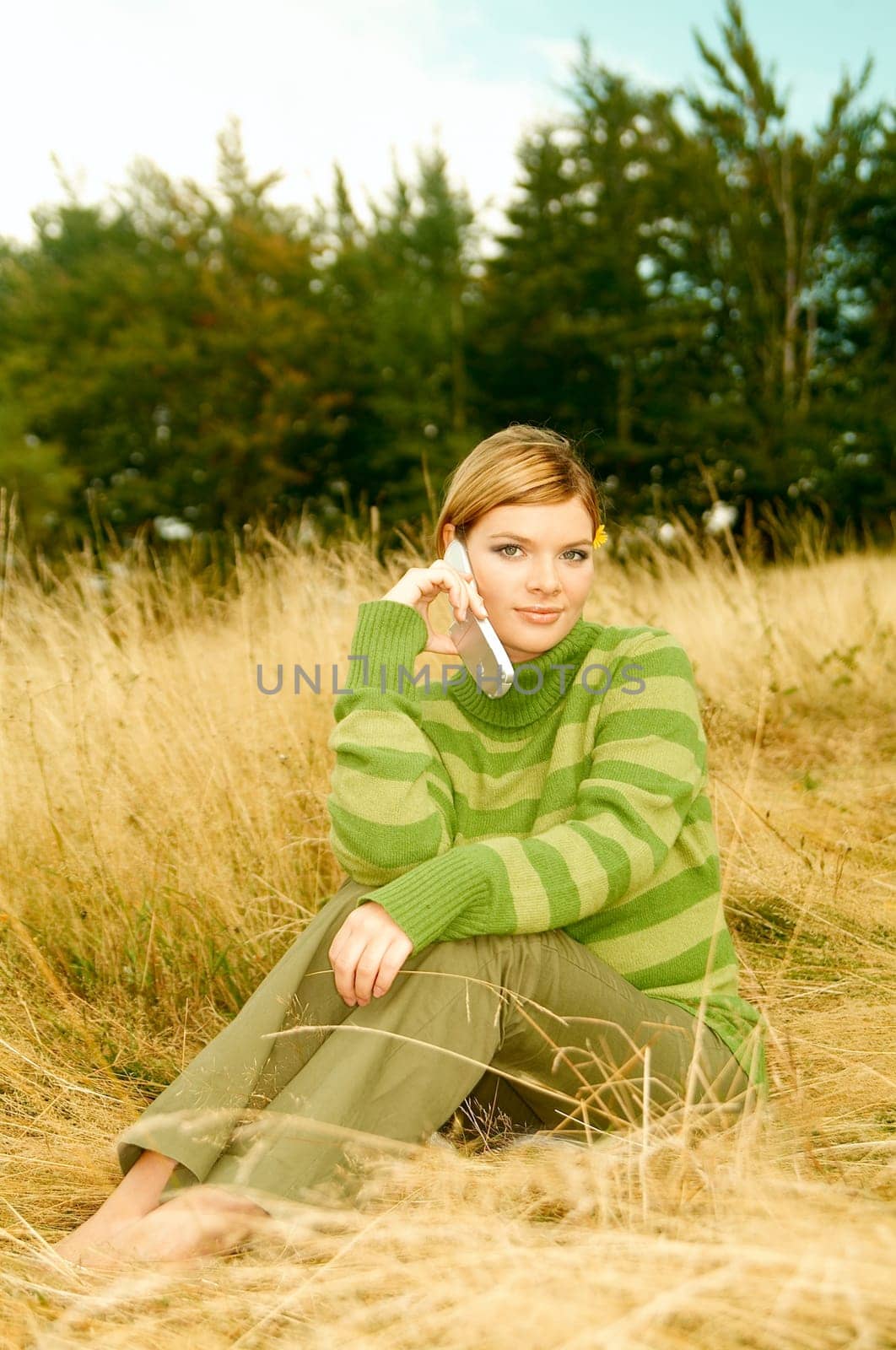 Young business woman using cell phone on golden meadow at mountains outdoors