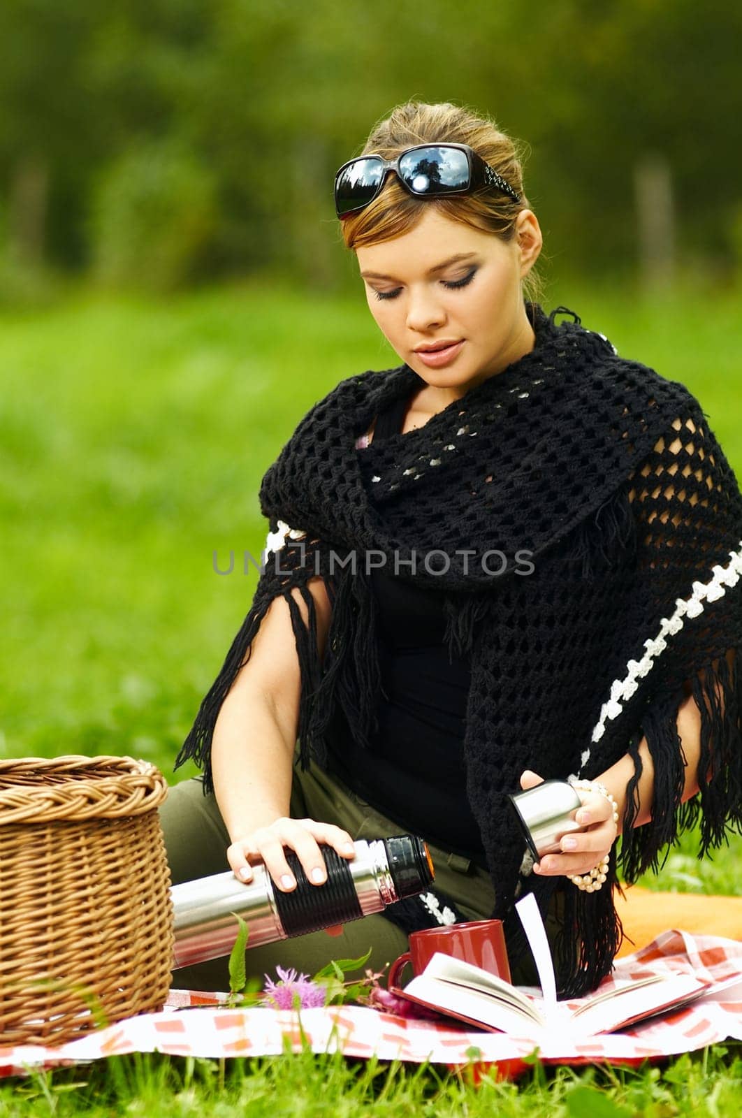 Young business woman with cup during picnic on green meadows outdoors