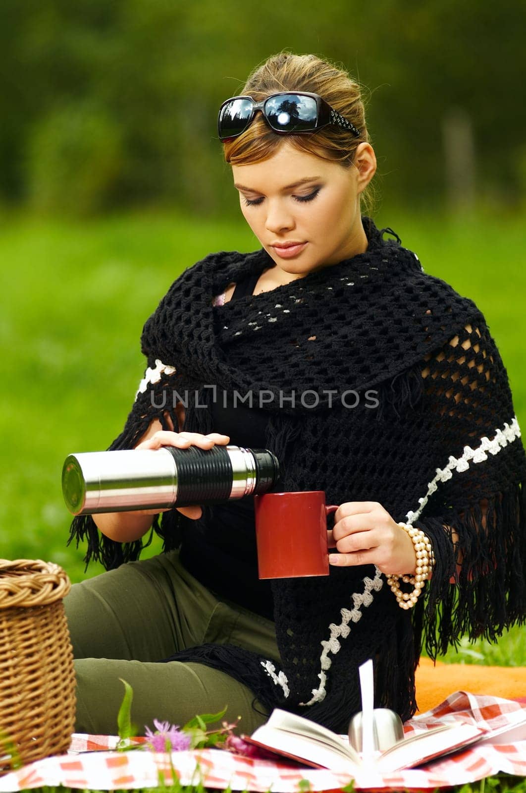 Young business woman with cup during picnic on green meadows outdoors