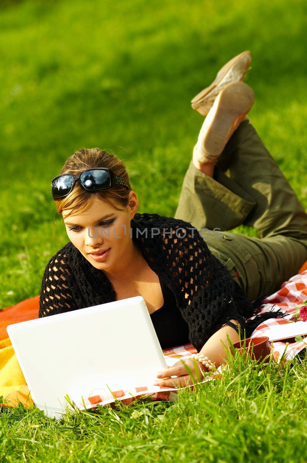 Young business woman working on laptop computer during picnic on green meadows outdoors