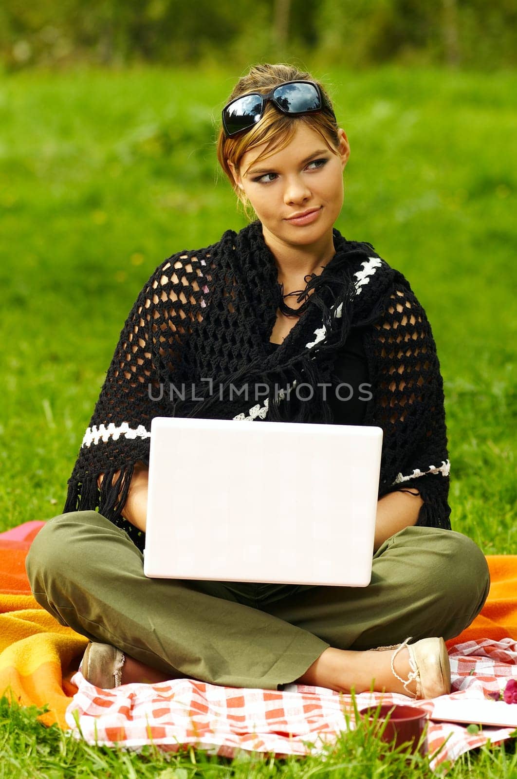 Young business woman working on laptop computer during picnic on green meadows outdoors