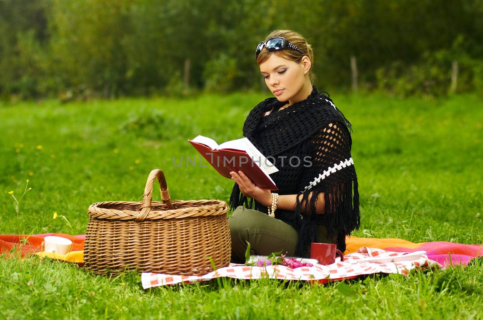 Young business woman with book during picnic on green meadows outdoors