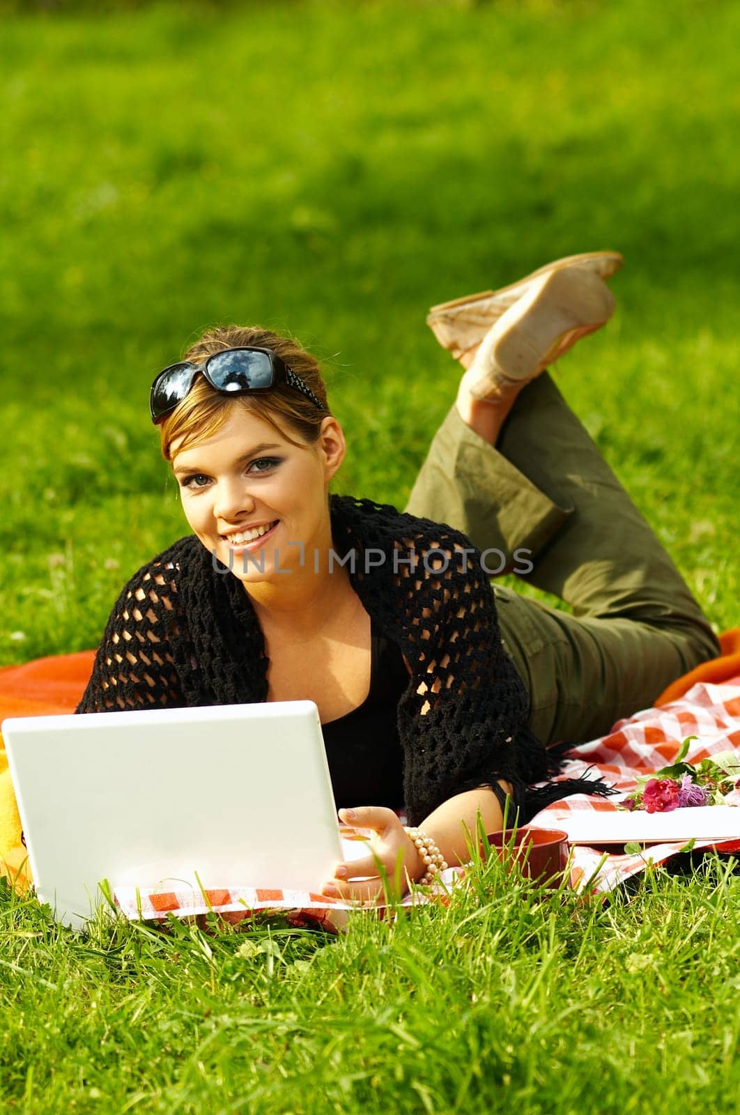 Young business woman working on laptop computer during picnic on green meadows outdoors