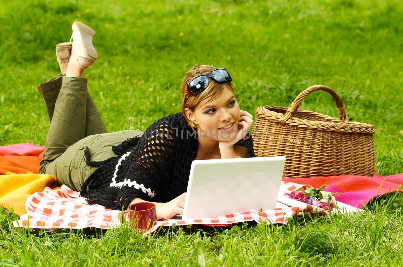 Young business woman working on laptop computer during picnic on green meadows outdoors