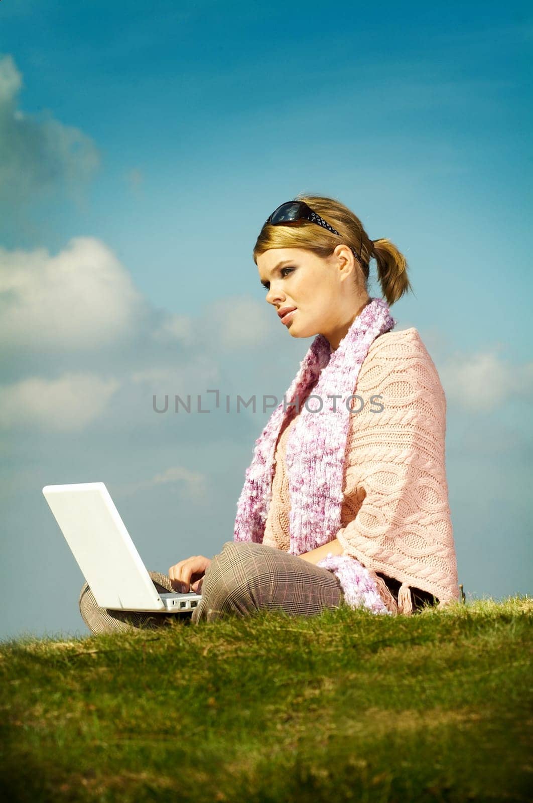 Young business woman relaxing, working on laptop computer on meadow