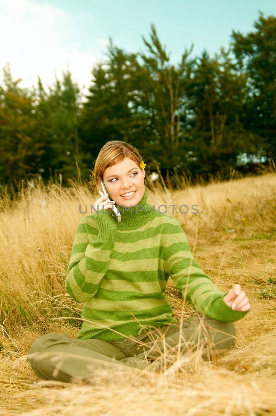Young business woman using cell phone on golden meadow at mountains outdoors