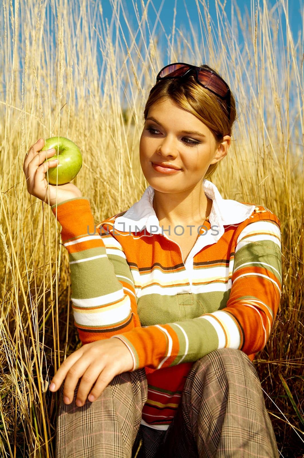 Young business woman relaxing on meadow, holding green fresh apple